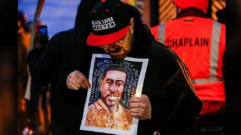 A man holds an image of George Floyd at a vigil on the second anniversary of the death of Floyd