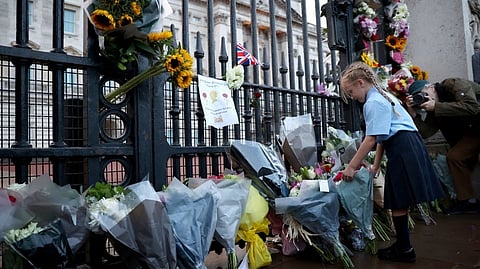 A girl places flowers outside Buckingham Palace