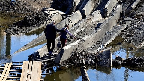 Local residents make their way through the ruins of the bridge that was destroyed during the fighting between Russian troops and Ukrainian army