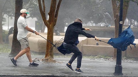 Wind gusts, blowing down King Street, twist umbrellas during Hurricane Ian in Charleston.