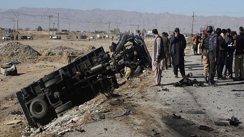 Police officers in civilian clothes survey the aftermath of a suicide bomb blast on a police patrol