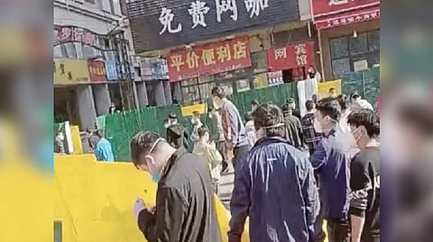 A group of people cross a downed fence following a protest at Foxconn's plant in Zhengzhou, China
