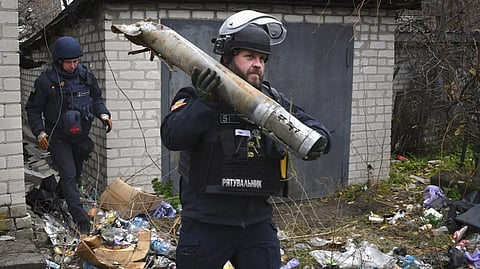 A Ukrainian sapper carries a part of a projectile during a demining operation in a residential area in Lyman, Donetsk region, Ukraine.