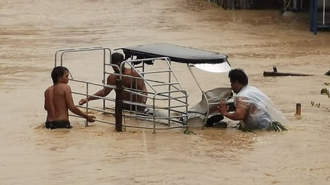 People moving a vehicle in a marooned area.