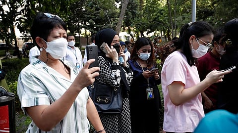 People gather as they are evacuated outside a building following an earthquake in Jakarta, Indonesia.