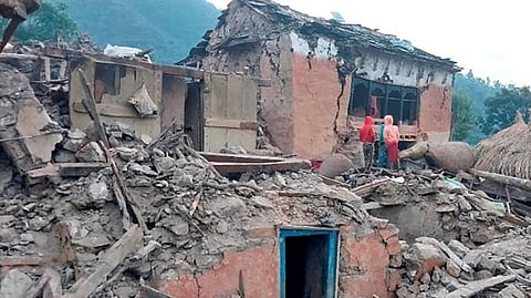 People outside the ruins of collapsed houses in the district of Doti after an earthquake struck Nepal .
