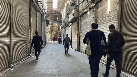 People walk through closed shops of Tehran's Grand Bazaar, Iran, Tuesday.