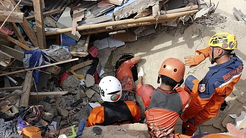 Rescuers search for victims under the rubble of a building collapsed during Monday's earthquake in Cianjur