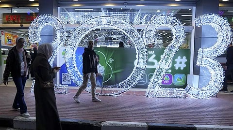 Palestinian girls take photos of themselves in front of illuminated numbers for the new year 2023, at the main road in Gaza City,