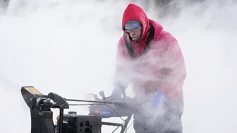 Mark Sorter clears snow from a downtown ice skating rink, Friday, Dec. 23, 2022, in Des Moines, Iowa.