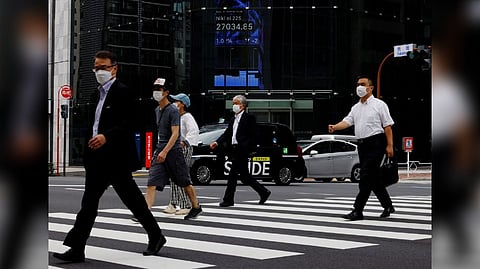 People pass by an electronic screen showing Japan's Nikkei share price index inside a commercial building in Tokyo
