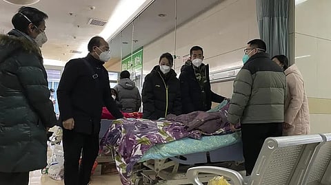 A man pulls a cloth to cover up the face of an elderly woman whose vitals flatlined as emotional relatives gather silently around her for a final farewell before her body is taken away at the emergency department of the Langfang No. 4 People's Hospital in Bazhou city in northern China's Hebei province.