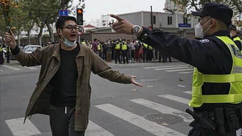 A protester holding flowers is confronted by a policeman during a protest on a street in Shanghai, China.