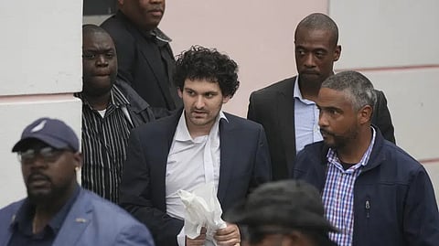 FTX founder Sam Bankman-Fried, center, is escorted from the Magistrate Court in Nassau, Bahamas, Wednesday, Dec. 21, 2022, after agreeing to be extradited to the US.