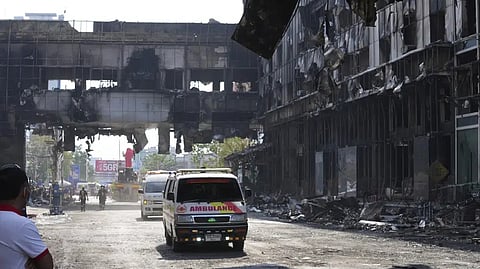Thai ambulances drive through a ruined building as they head back toward Thailand border