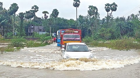 Vehicles struggling to navigate the submerged causeway of Sitheri Lake in Bolivakkam, Tiruvallur on Saturday