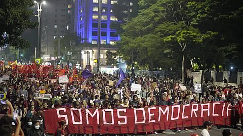 Demonstrators march holding a banner that reads in Portuguese "We are Democracy"