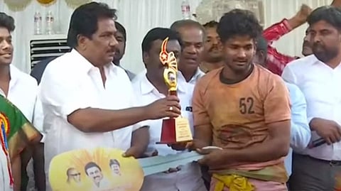 Abhi Siddhar, who tamed 26 bulls and secured first place in the Jallikattu event in Madurai receives trophy,