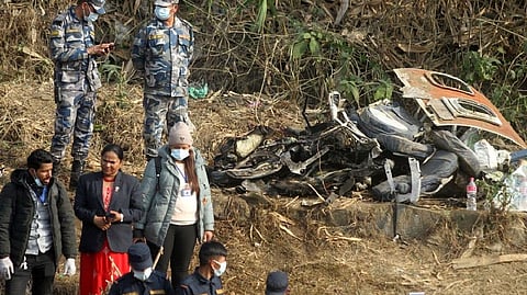 People and guards standing nearby wreckage