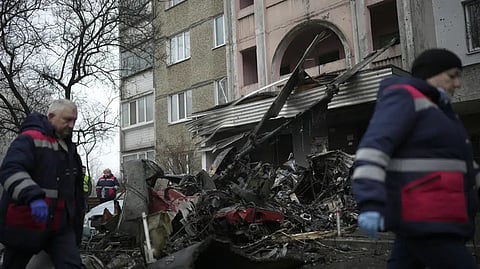 Workers pass the scene where a helicopter crashed on civil infrastructure in Brovary.