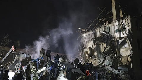 Emergency workers and local residents clear the rubble after a Russian rocket hit an apartment building in Kramatorsk