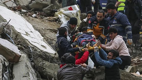 People and emergency teams rescue a person on a stretcher from a collapsed building in Adana, Turkey.