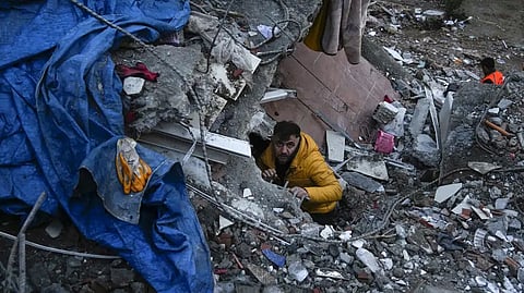 A man searches for people in a destroyed building in Adana, Turkey, Monday.