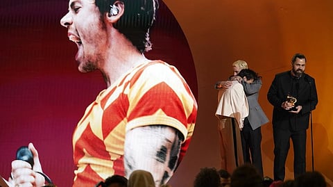 Harry Styles, left, embraces Kid Harpoon, center, while Tyler Johnson accepts the award for album of the year for "Harry's House" at the 65th annual Grammy Awards on Sunday.