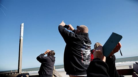 People photograph a suspected Chinese spy balloon as it floats off the coast in Surfside Beach