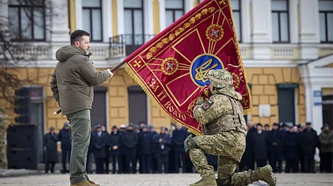 Ukrainian President Volodymyr Zelenskyy, left, holds the flag of a military unit as an officer kisses it, during commemorative event on the occasion of the Russia Ukraine war one year anniversary in Kyiv, Ukraine.