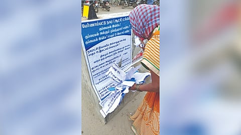 A worker removing the posters in Pernambut Municipality on Thursday