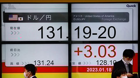 Passersby walk past electric monitors displaying the exchange rate between the Japanese yen against the U.S. dollar outside a brokerage in Tokyo, Japan