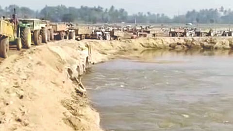 Lorries moving out of Palar river with mined sand in Vellore