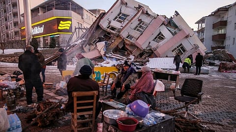 People stand by collapsed buildings in Golbasi, in Adiyaman province, southern Turkey