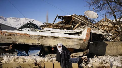 Zehra Kurukafa walks past a destroyed house in the village of Polat, Turkey