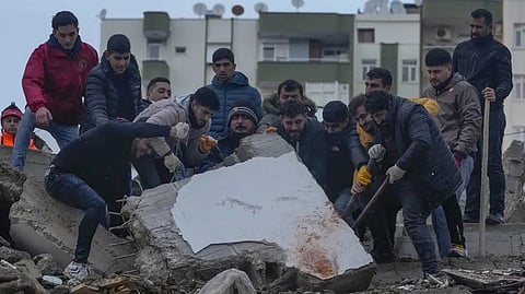 Men search for people among the debris in a destroyed building in Adana, Turkey, Monday.