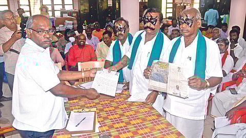 Farmers, wearing masks, hand over their petition to RDO Palanivel.
