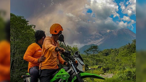 Men watch as Mount Merapi releases volcanic materials during an eruption in Sleman, Indonesia, Saturday, March 11, 2023