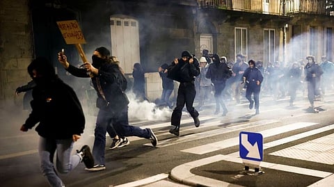 Protesters run amid clashes as they attend a demonstration on the day the National Assembly debates and votes on two motions of no-confidence against the French government