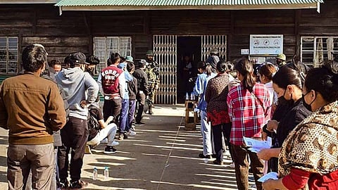 Voters wait in queues to cast their votes at a polling booth during the Nagaland Assembly elections on Monday