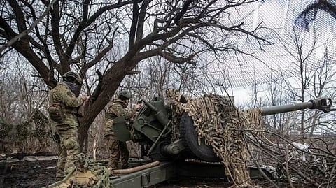 Ukrainian service members prepare to shoot from a howitzer