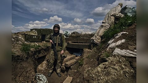 A Ukrainian soldier smiles standing in a trench on the frontline in the village of New York