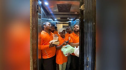 A photo of five Swiggy delivery agents inside an elevator to deliver food orders