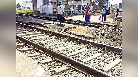 Commuters cross the track at Putlur railway station