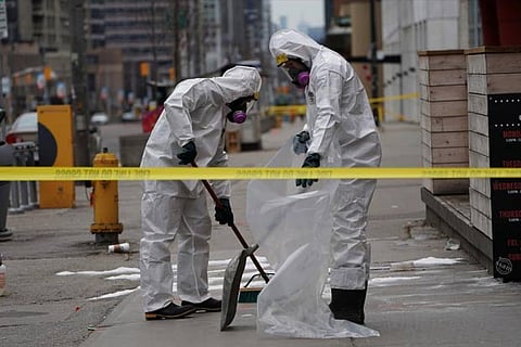 A work crew in protective clothing cleans a sidewalk a day after a van struck multiple people
