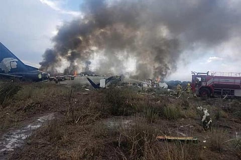 Firefighters douse a fire as smoke billows above the site where an passenger jet crashed