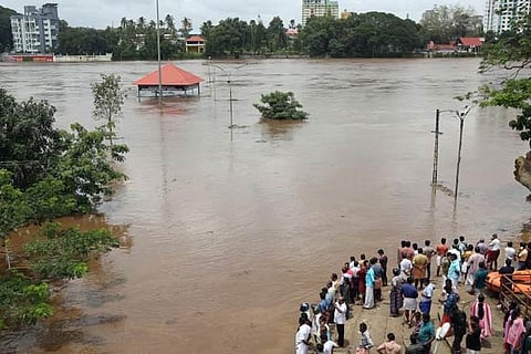 People stand on the steps of Kochi's Aluva Shiva Temple complex submerged in water, Kerala