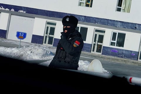 A policeman is seen through a car window at a security check point into Khom village