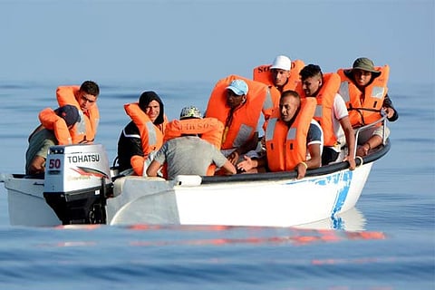 Migrants are seen on board a fiberglass boat in the Mediterranean Sea