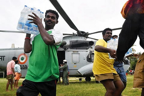 People carry flood relief material to be sent to flood-affected areas in Thiruvalla